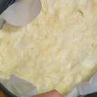 Разъемную форму выстелить бумагой для выпечки и равномерно распределить тесто, так чтобы получились небольшие бортики.