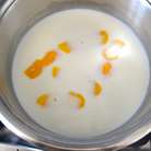 Тем временем приготовьте крем. В кастрюлю налейте молоко и добавьте срезанную цедру половины лимона. Поставьте закипать на огонь. 