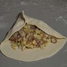 Преступаем к формированию треугольников. Отщипываем кусочек теста и раскатываем в лепешку и на середину выкладываем начинку и соединяем формируя 1й угол.