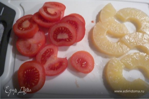 Разогреть духовку до 200°C. Помидоры помыть, нарезать кольцами, ананасы - пополам.