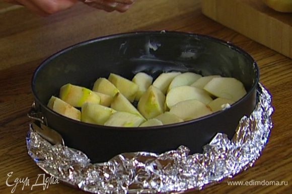 Смазать сливочным маслом разъемную форму (при необходимости выстелить фольгой, чтобы тесто не вытекало) и уложить в нее дольки яблок как можно плотнее друг к другу.