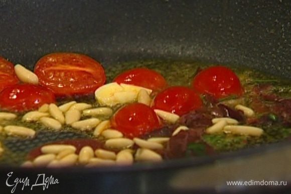 Выложить в сковороду к чесноку помидоры, оливки вместе с заправкой и кедровые орехи и обжаривать 1–2 минуты.