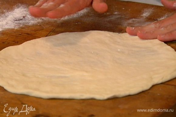 Раскатать тесто в тонкий пласт. Перевернуть противень вверх дном, присыпать его мукой и выложить на перевернутый противень раскатанное тесто.