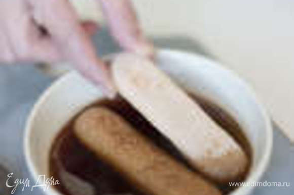 В заваренный кофе добавить коньяк и пропитать кусочки бисквита.