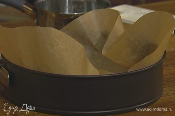 Разъемную форму выстелить бумагой для выпечки, смазанной с обеих сторон сливочным маслом. Выложить тесто в форму, равномерно распределить тонким слоем и поставить на 5 минут в морозильную камеру.