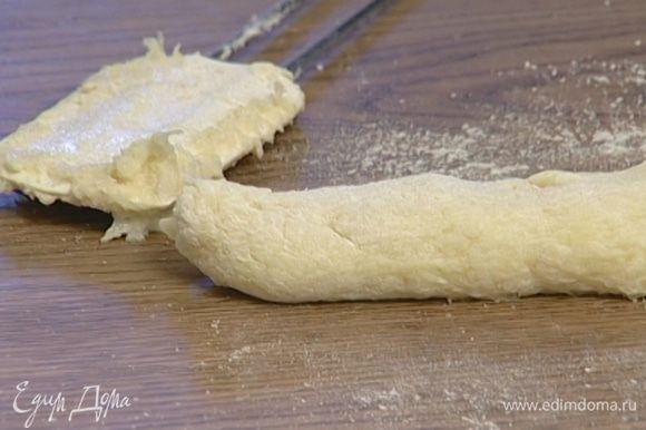Остальную муку высыпать на рабочую поверхность, выложить тесто и сформировать из него колбаску диаметром 2–3 см.
