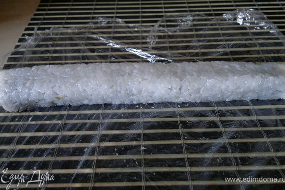сворачиваем ролл с помощью бамбукового коврика, сворачиваем с той стороны, гда мы оставляли 2 сантиметра без риса