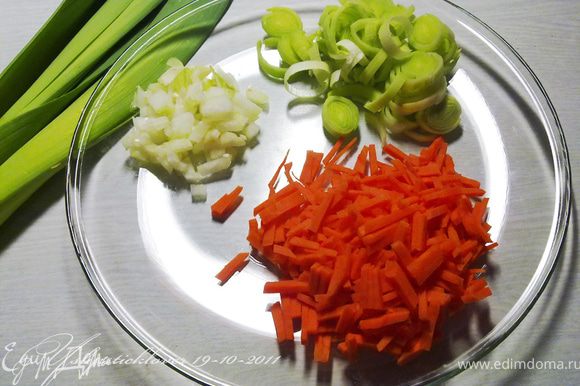 Оставшиеся 3 листа капусты нашинковать. Лук-порей нарезать кольцами, 1 морковь нашинковать соломкой, 1 луковицу мелко нарезать. Грибы разморозить и нарезать на кусочки.