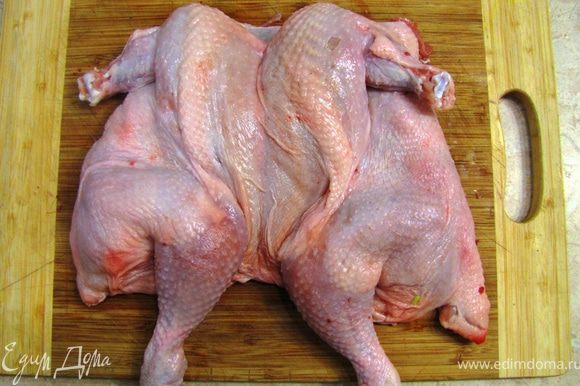 Переверните курицу и постарайтесь ее вывернуть, чтобы она стала "плоской". Стукните по ней кулаком, чтобы косточки сломались и она полностью легла на доску.