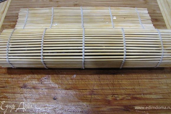 Придерживая пальцами начинку начните заворачивать ролл вместе с бамбуковым ковриком. Как только вы сделаете один оборот, сразу высвобождайте бамбуковый коврик, чтобы он не завернулся внутрь ролла.