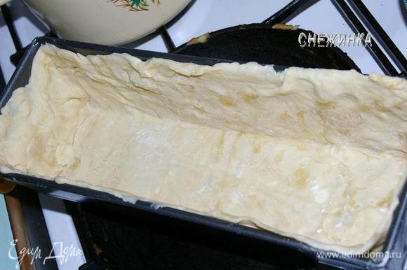 Слоеное тесто разделить на две части, одну немного больше другой. Взять бОльшую часть, раскатать на присыпанной мукой поверхности в прямоугольник и выстелить прямоугольную форму для выпечки так, чтобы тесто заполнило дно и бока формы.