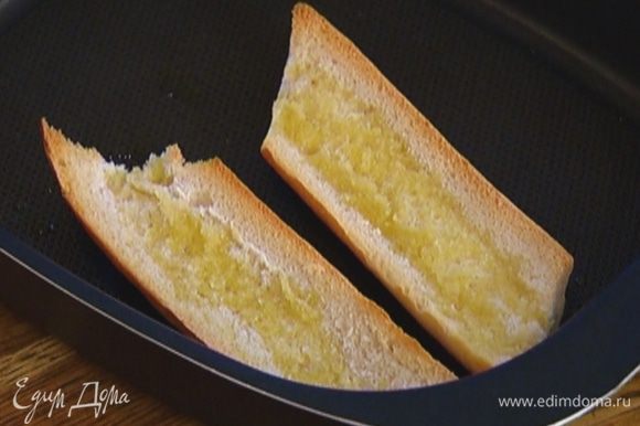Выложить хлеб на противень срезами вверх, сбрызнуть оливковым маслом и обжаривать в разогретой духовке до появления золотистой корочки.