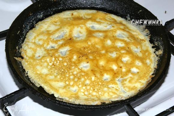 Когда края яйца начнут подсыхать и золотиться, убираем сковороду с огня, даем постоять 20 секунд, и осторожно переворачиваем омлет на другую сторону. Дожариваем 30 секунд.