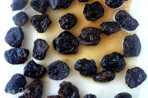 В смазанную сливочным маслом форму выложить чернослив и несколько минут прогреть в разогретой до 220 градусов духовке.