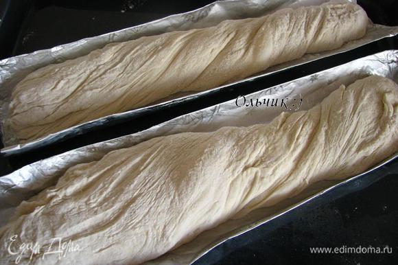 Присыпаем тесто мукой со всех сторон, аккуратно разделяем его на 2 части. Легкими движениями формируем багеты, слегка перекручиваем тесто одновременно вытягивая его по длинне формы. Укладываем в формы.