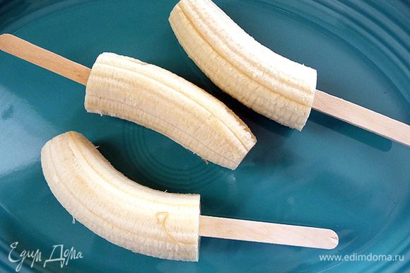 Берем банан и режем его на 2-3 части. И одеваем на эти части деревянные плочки.