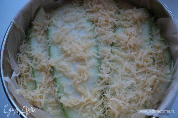 Снова выложить слой кабачков, укладывая их перпендикулярно нижнего слоя. Затем сыр, базилик, соус и так далее. Сверху посыпать оставшимся сыром.