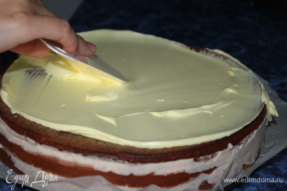 Сливки для украшения торта взбить, большую часть покрасить в желтый цвет и выложить на поверхность торта. Разровнять широким ножом. А меньшую часть переложить в шприц (будем украшать наш верх торта).