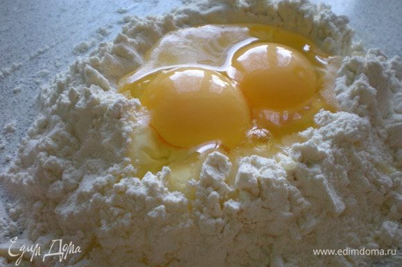 Тесто. Насыпать муку на стол, сделать кратер (ямку), разбить яйца и добавить оливковое масло.