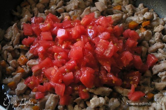Через 2 минуты добавить очищенные от кожи и семян помидоры, нарезанные маленькими кусочками, перемешать.