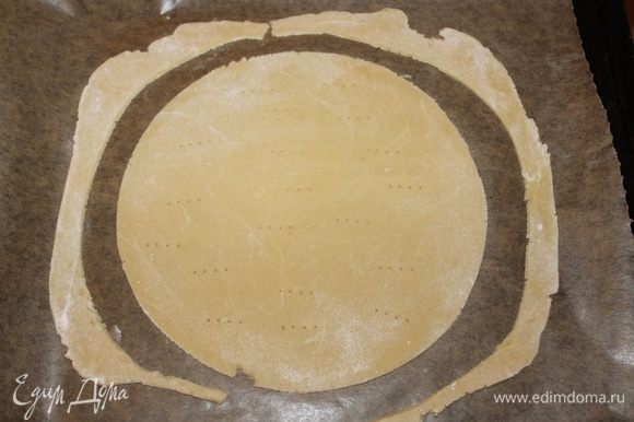 Выложите корж на противень на лист пекарской бумаги, сделайте проколы вилкой, чтобы при выпекании не образовались пузыри. Обрезки выпекайте вместе с коржом.