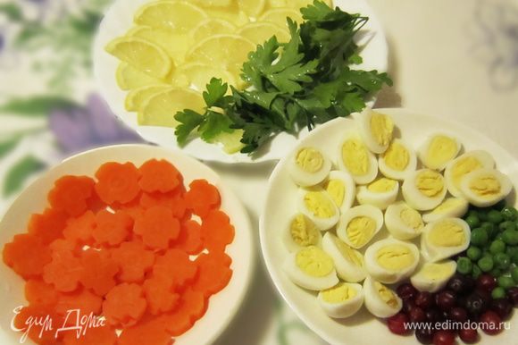 Тем временем подготовьте украшение из моркови, отварите и нарежьте перепелиные яйца, нарежьте тонкими дольками лимон, помойте листики петрушки, подготовьте клюкву и горошек. Украшайте, чем хотите — здесь фантазия не ограничена!