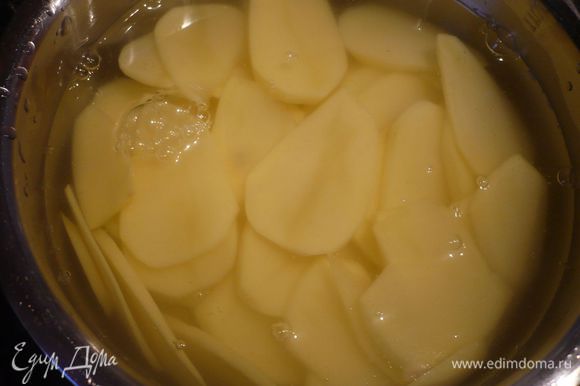 Полтора килограмма картофеля сварить в мундире, остальные 500 г почистить, нарезать вдоль тонкими кольцами (1-2 мм) и залить водой.