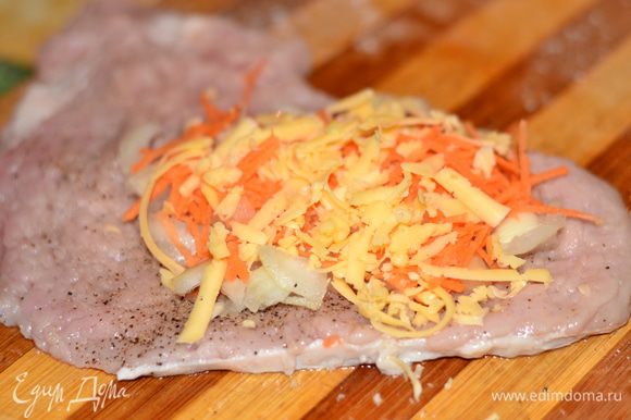 На отбитое, посоленное и приправленное мясо положить лук, морковь, сыр.