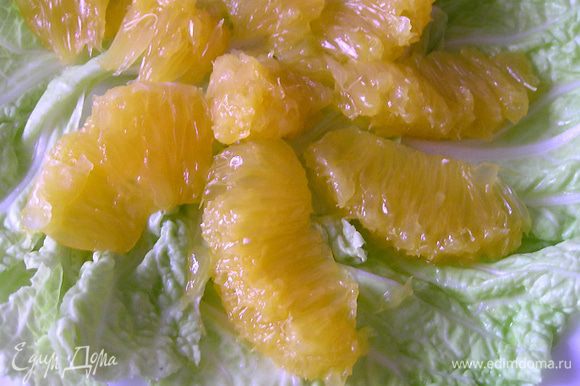Листья салата разложить по тарелкам, добавить очищенные от пленок дольки апельсина,