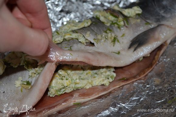 Рыбу выложить на смазанную растительным маслом фольгу. внутрь рыбы кладем застывшее масло и с верху на ней тоже раскладываем кусочки масла.