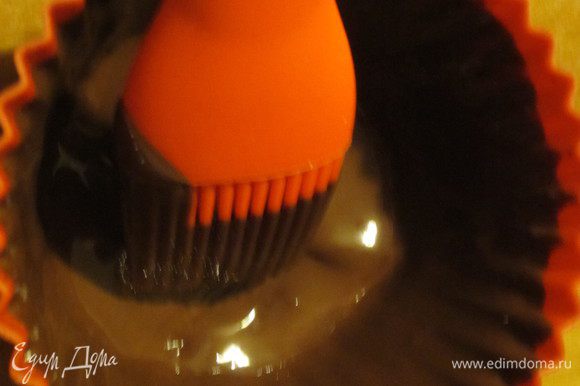 Кисточкой нанести слой шоколада на стенки силиконовых формочек для маффинов. Поместить в холодильник на 1 час.