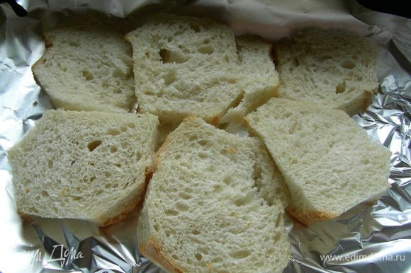 Хлеб режем ломтиками и срезаем корки. Выкладываем его на противень, застеленный бумагой для выпечки.