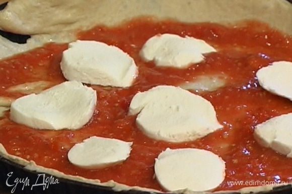 Круглую форму для выпечки смазать оливковым маслом, уложить в нее тесто, равномерно смазать пласт томатной массой, сверху разложить моцареллу.