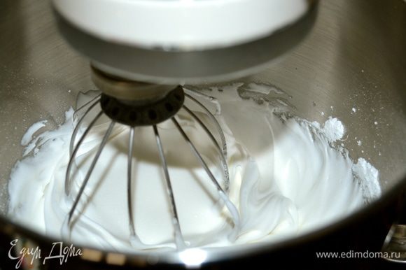 Начать взбивать белки с щепоткой соли (лучше всего с помощью электромиксера или кухонного комбайна). Как только белки взобьются до мягких пиков, начать добавлять оставшуюся одну треть сахарной пудры...по столовой ложке.