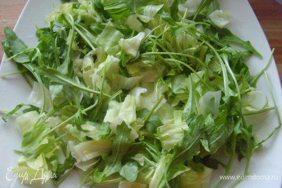 На блюдо выложить салатные листья, полить половиной заправки.