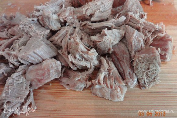 Готовое мясо вынуть из бульона, чуть остудить и порезать на небольшие кусочки.