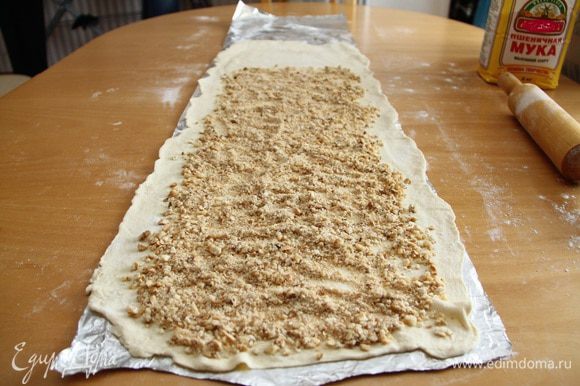 Выложить на тесто орехово-печенюшные крошки таким образом, чтобы по краям слева и справа оставалось чистое тесто 3-5 см, а на дальнем от вас крае - 10-15 см.