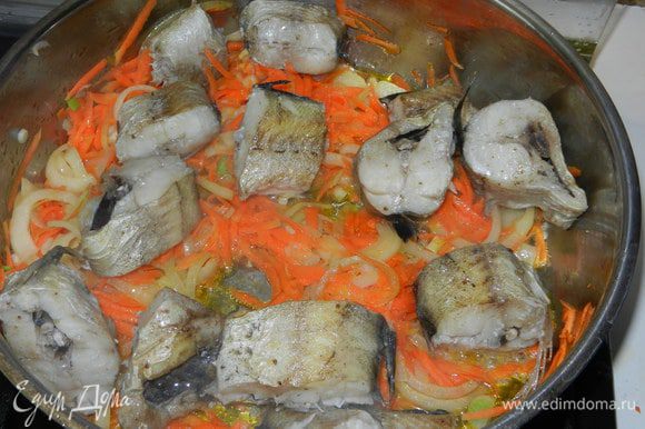 В сотейнике пассеруем тонко нарезанный лук полукольцами и натертую на крупной терке морковь до полуготовности. Добавляем соль и смесь перцев. Выкладываем на "подушечку" нашу рыбу и на медленном огне тушем несколько минут под крышкой.