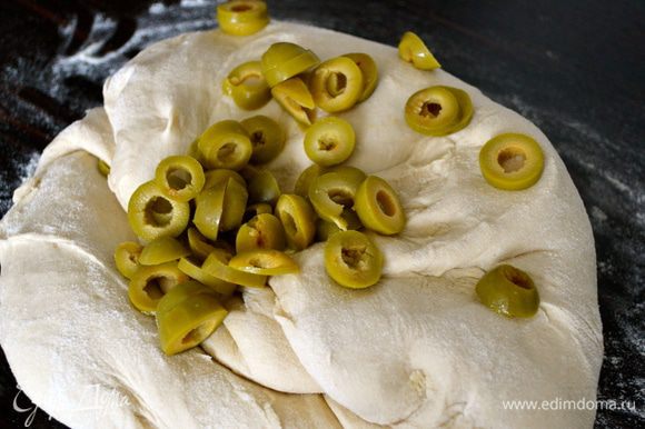 Выложить тесто на присыпанную мукой поверхность и добавить постепенно в него оливки.