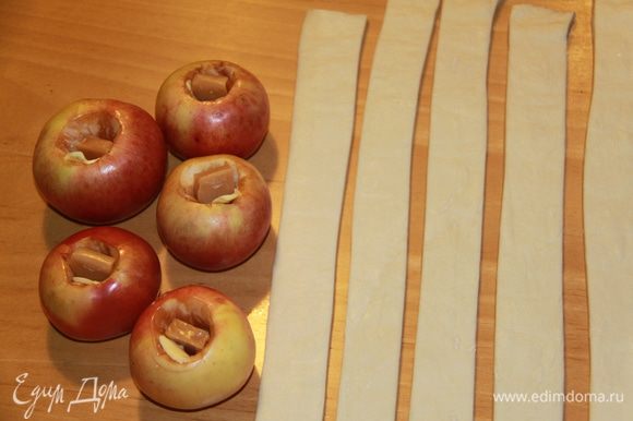 Подготовить яблоки: вымыть, удалить сердцевину, но не прорезая дно. Внутрь каждого яблока кладём кусочек масла и ириску (у меня "Кис-кис"). Тесто нарезаем на полоски.