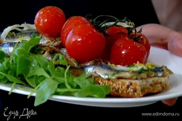 Запеченные сардины выложить на хлеб, подавать с запеченными помидорами и листьями салата.