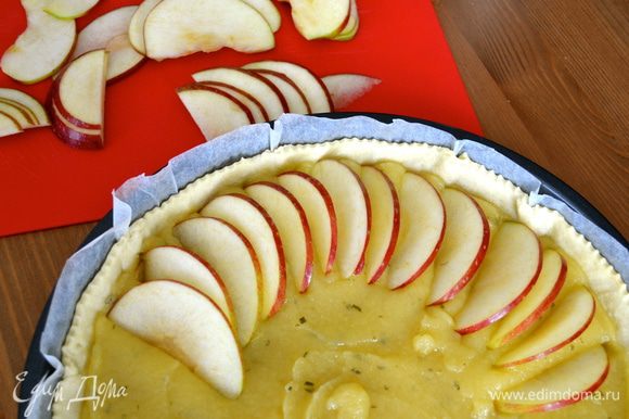 Два красных яблока, не очищая кожуры (удалить только сердцевину с косточками), нарезать тонкими дольками, и выложить их по кругу на поверхности пирога.