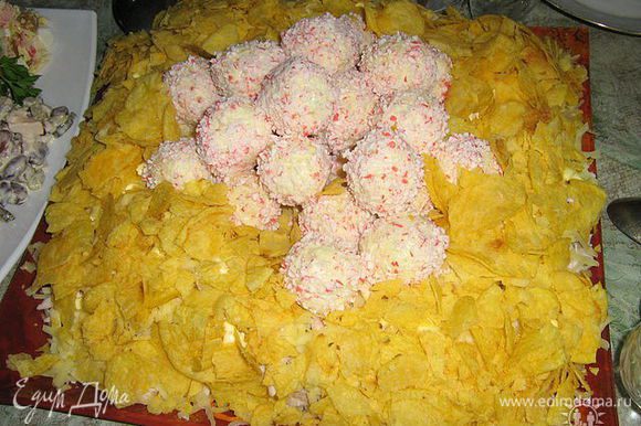 сырные шарики обвалять в крошках крабовых палочек и выложить в центр салата поверх чипсов