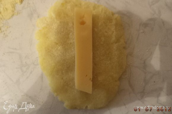 Сыр нарезать брусочками. Из картофельной массы сформировать небольшие лепёшки. На середину каждой лепёшки положить брусочек сыра, края защипать.