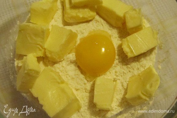 Для приготовления коржа-основы в миску просеять муку, добавить сливочное масло комнатной температуры, желток и щепотку соли.