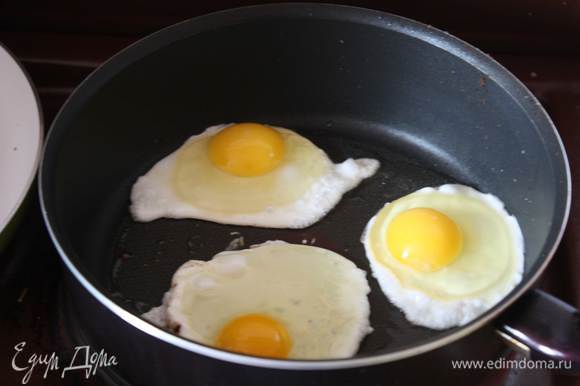 Убираем хлеб со сковороды, вытираем ее бумажной салфеткой и пожарим 2-3 яйца, каждое отдельно, чтобы не соприкасались. Готовим их 6-7 минут, так чтобы желток остался жидким.