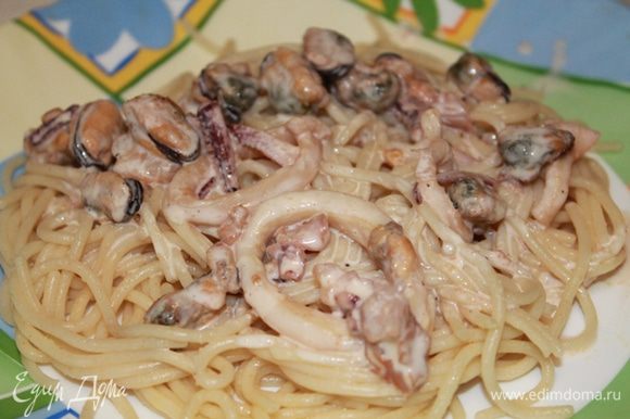 На блюдо выложить спагетти, сверху морепродукты и полить сырно-сливочным соусом.