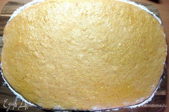 Когда тесто подойдет, выложить его на посыпанную мукой доску. Слегка припылить тесто мукой и раскатать скалкой в прямоугольник толщиной около 1 см.