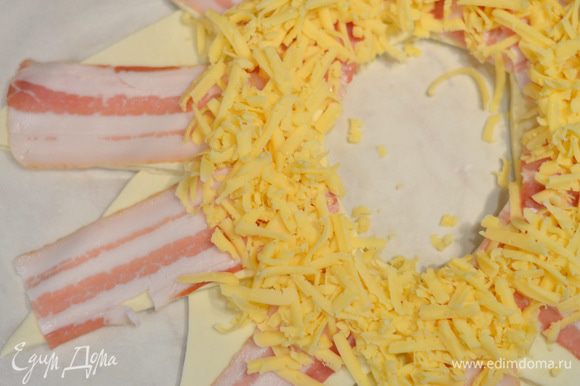 Натереть сыр на терке и выложить половину по кругу.
