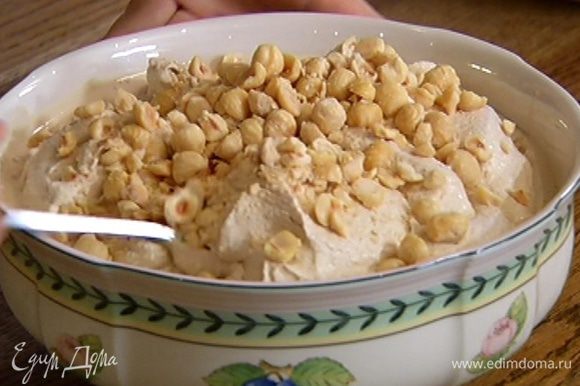 В готовое мороженое добавить измельченные орехи и перемешать. Каждую порцию мороженого украсить оставшимися целыми орехами.